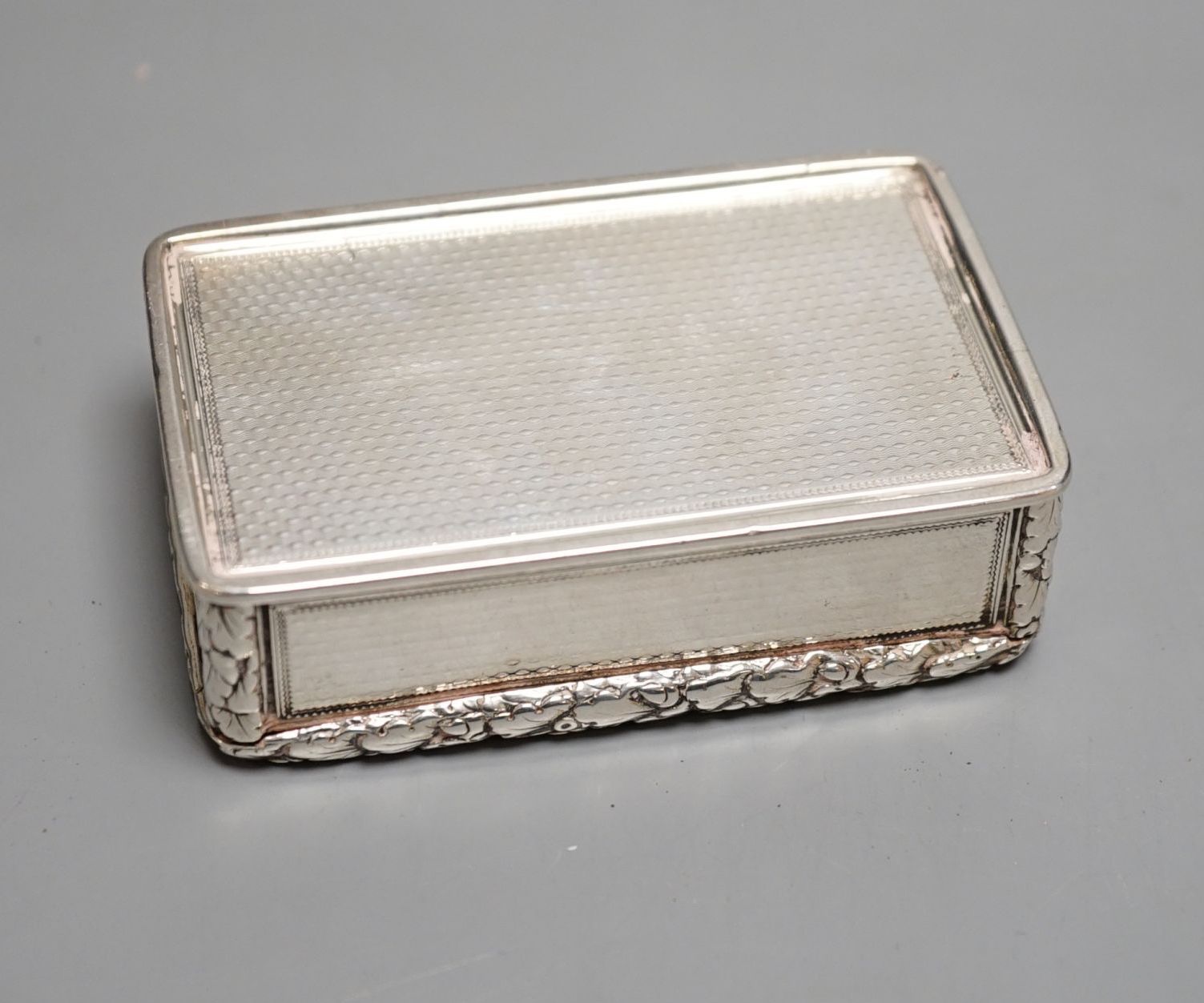 A George IV engine turned silver rectangular snuff box, with yellow metal applique, Charles Rawlings, London, 1827, 82mm.